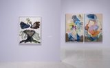 A gallery with lavender walls displays three paintings: a portrait with birds and branches on the left and two colorful abstract pieces side by side on the right. The floor is polished and reflective.