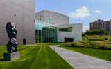 The back of the Walker Art Center with a large grass yard and a art sculpture on a sunny day.