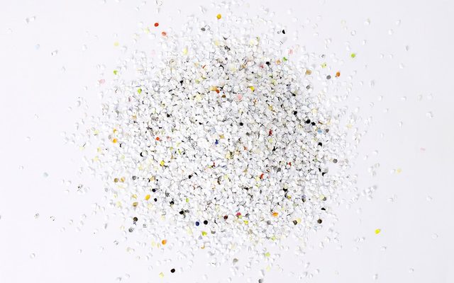 White confetti with bits of color in a pile on top of a white surface