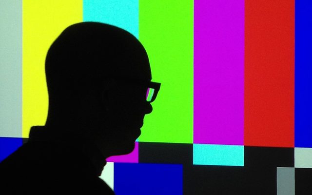 a sillohuette of a bald adult with eyeglasses in front of a bars and tone screen