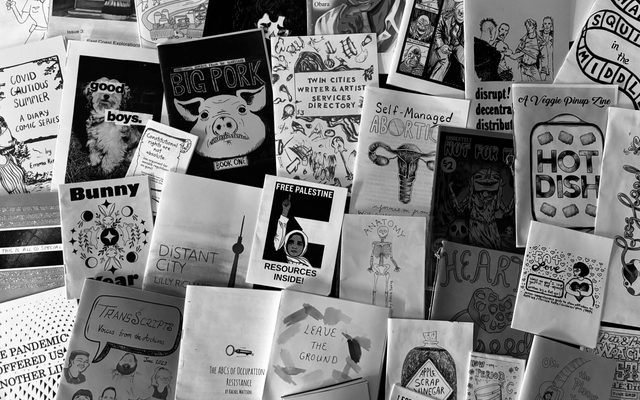 Black and white image of several zines laid out on a table.