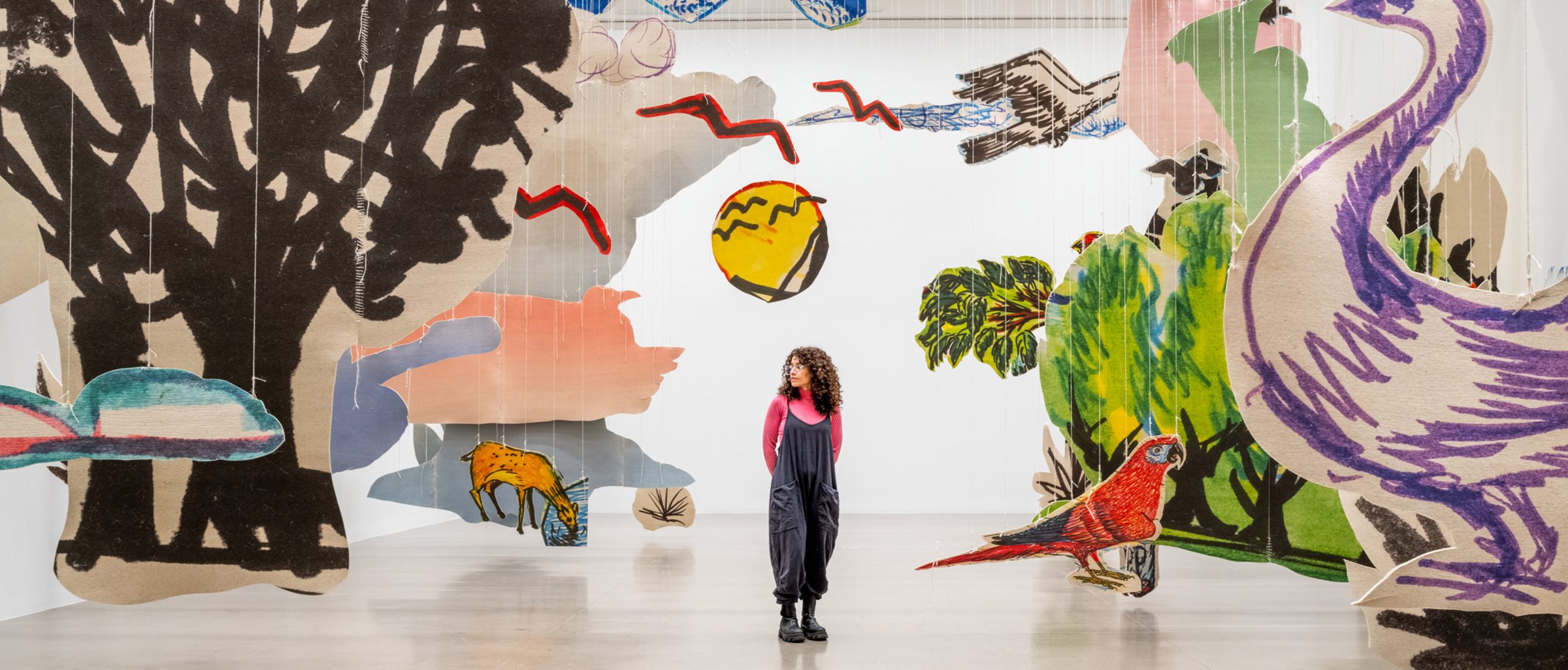 An adult standing in the middle of a large paper art installation