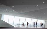 People stand in front of a large window in an empty event space at the Walker Art Center