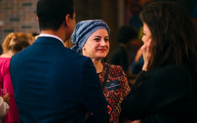 An adult wearing a cultural headdress listening to others in a small group