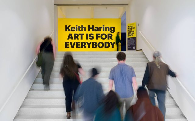 People walking up the stairs towards a sign reading 