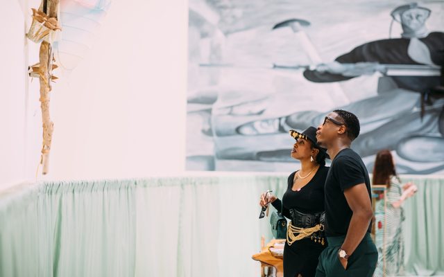Two adults standing and looking up at an art piece hanging on the wall at a Walk Art Exhibit