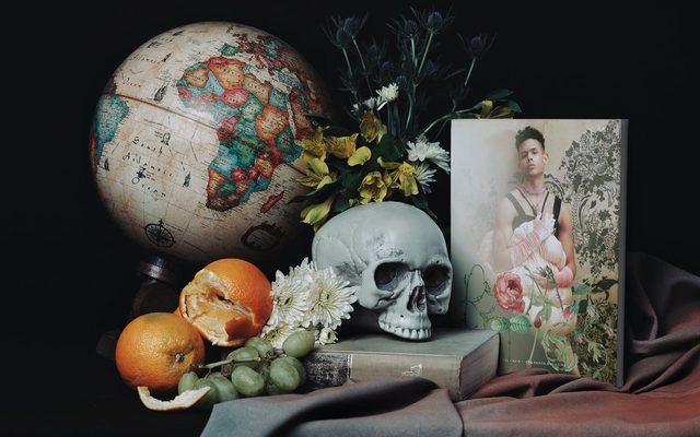 Still life of skull, oranges, globe, magazine, flowers