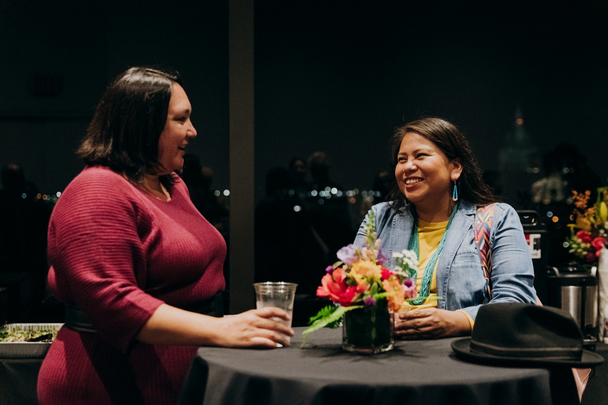 Two adults hold drinks and smile at one another.