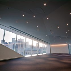 A empty large event space at the Walker Art Center with big windows and small round ceiling lights