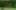 a horizontal image of a large room with columns made from packed earth sitting on a chromakey green surface that sits inches off of the floor. The blurred silhouette of a person walks past in the foreground.