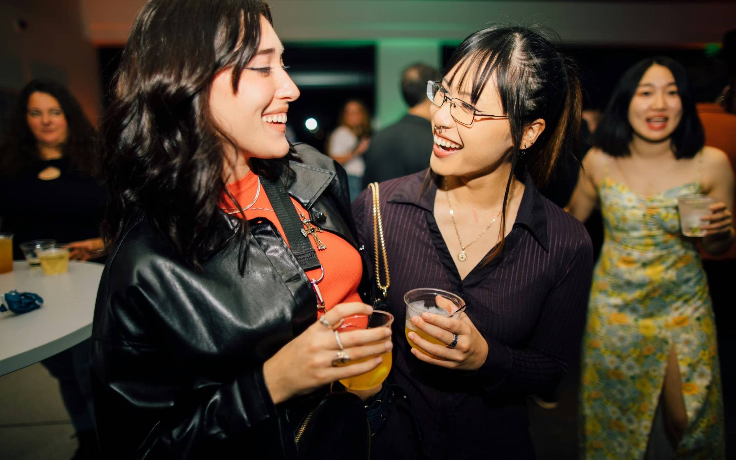 Two people dressed for a party smile at one another in the Walker lobby. They both hold a drink.