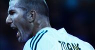 Close profile of a soccer player in motion and shouting - a white man with buzzed hair, sweaty, and wearing a white jersey with ZIDANE on the back.