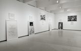 Art gallery with framed black-and-white photos and handwritten text displayed on white walls.