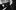 A man with short, curly hair sits at a piano, resting his head on one hand and holding a pair of glasses in the other. Sheet music is visible on the piano, and the background is softly out of focus.