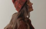 A woman wearing a fuzzy, rust-colored beanie and matching sweater, looking to the side.